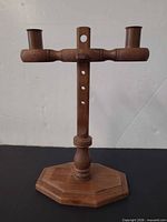 Front view of wooden candlestick showing full structure and brass cups