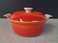 Front view of orange-red Dutch oven with lid on