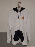 Front view showing white hoodie, navy hood lining, contrast pockets, full zipper, chest graphic