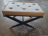 Three-quarter view of bench showing cushion, X-frame legs and chrome caps