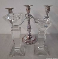 Pair of crystal candlesticks flanking silver-plated three-arm candelabra