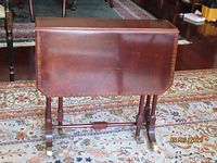 Table with leaves folded showing front and legs on brass casters
