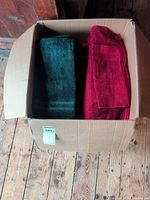 Box containing green and red bath towels