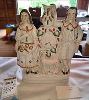 Front view of figural spill vase showing woman, man, tree trunk, dog