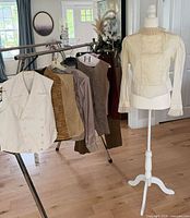 Rack with white vest, patterned garments and mannequin blouse