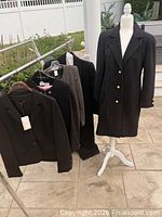 Front view of black wool Bally coat on mannequin showing length, lapel and gold buttons