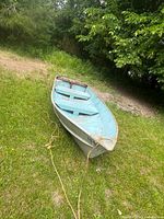 Rowboat full view on grass, rope at bow