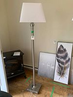 Full view of brushed metal floor lamp with shade and square base