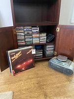 Open cabinet showing cassette tapes, CDs, vinyl records, Sony boombox