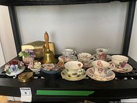 Entire lot on shelf showing teacups, saucers, figurines, bell, letter holder, boxes