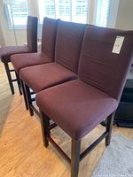 Four bar stools side by side showing slipcovers and wooden frames
