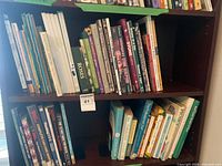 Two shelves of assorted gardening and craft books including Essential Shrubs and Roses
