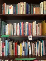 Three shelves filled with assorted hardcover and paperback books