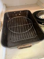 Black roasting pan with wire rack and circular rack placed inside