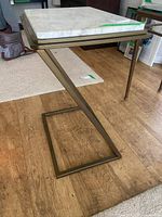 Side view showing Z-shaped brass frame and marble top