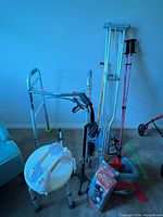 Group shot showing walker, crutches, walking poles, cane, raised seat with handle, knee support packages and tote