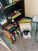 Overall lot on and beside bookshelf showing folders, stationery baskets, clock, envelopes and binders