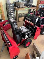 Left side view of complete snow blower showing auger housing, tires, control console and manual