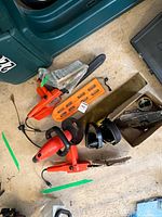 Overall lot showing two Remington chainsaws, Black & Decker hedge trimmer, ear muffs, blade guard, manuals