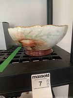 Side view showing shell motif, scalloped rim, gold trim, pedestal base