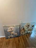 Both floral canvases side by side leaning on wall