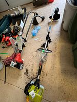 Both gas trimmers with accessories on garage floor