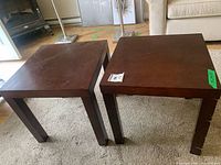 Two dark brown wooden square side tables side by side on carpet