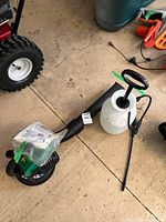 Blower and sprayer side by side on garage floor