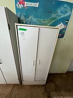 Front view of closed white cabinet showing double doors and handles