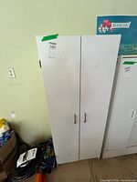 Front view of closed white cabinet with two metal handles