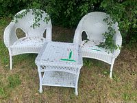 two white wicker armchairs and matching table outdoors