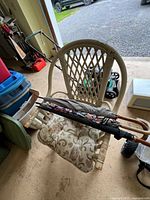 Overall view of wicker chair with cushion and umbrellas resting across seat