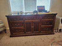 Front view of dark wood dresser showing six drawers, two central doors, brass hardware