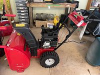 Left side view showing full snow blower, tires, engine, handle controls