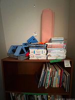 Lot overview showing yoga mat, water dumbbells, DVDs stack, books on shelf