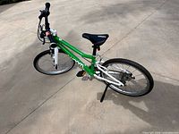 Left side view of green and white Woom kids bike on pavement