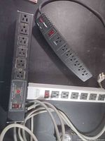 Three power strips on tabletop showing outlets and cords