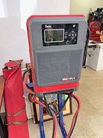 Front view of EnerSys NexSys+ charger showing display, grille, attached cables on mounting stand
