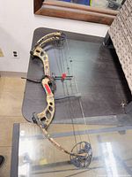 Full view compound bow on table showing limbs, cams, accessories