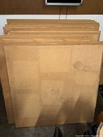 Stack of square particle board panels with visible stains