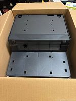 Black plastic housing seated in cardboard carton
