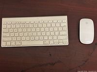 Top view of Apple Wireless Keyboard and Apple Magic Mouse on wooden surface