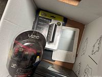 Box showing sealed Vizio HDMI cable 3-pack, packaged USB hub, Amazon Kindle e-reader, black optical drives