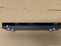 Front view showing Binary branding, power LED, source status LEDs, silver feet