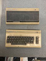 Two Commodore 64 units side by side showing overall condition, yellowing, and dust cover on one