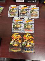 Seven Hot Wheels cars on cards displayed on table