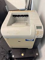 Front and top view of HP LaserJet P4015n printer showing control panel, output tray, and cosmetic wear