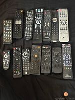 All fourteen remotes laid out on black surface
