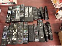 All 20 black remote controls laid out on table