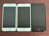 Front view of three iPhones showing screens and home buttons